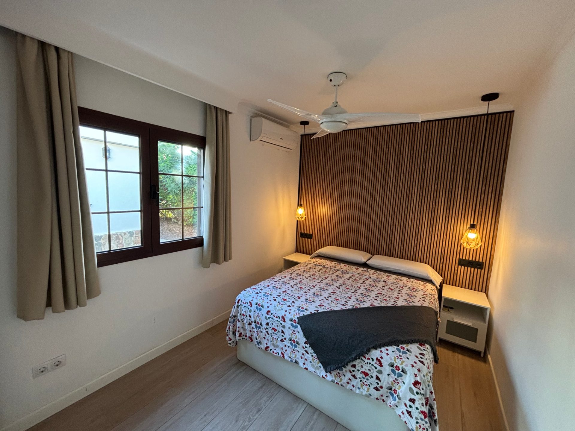 Bedroom with double bed, wood-slat wall and window to the garden