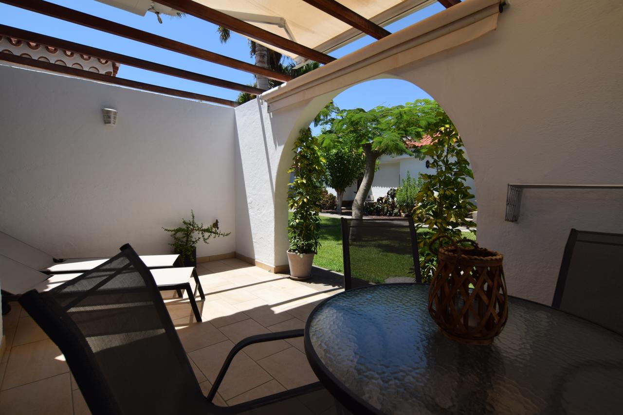 Private furnished terrace with table, chairs and garden view through the arch
