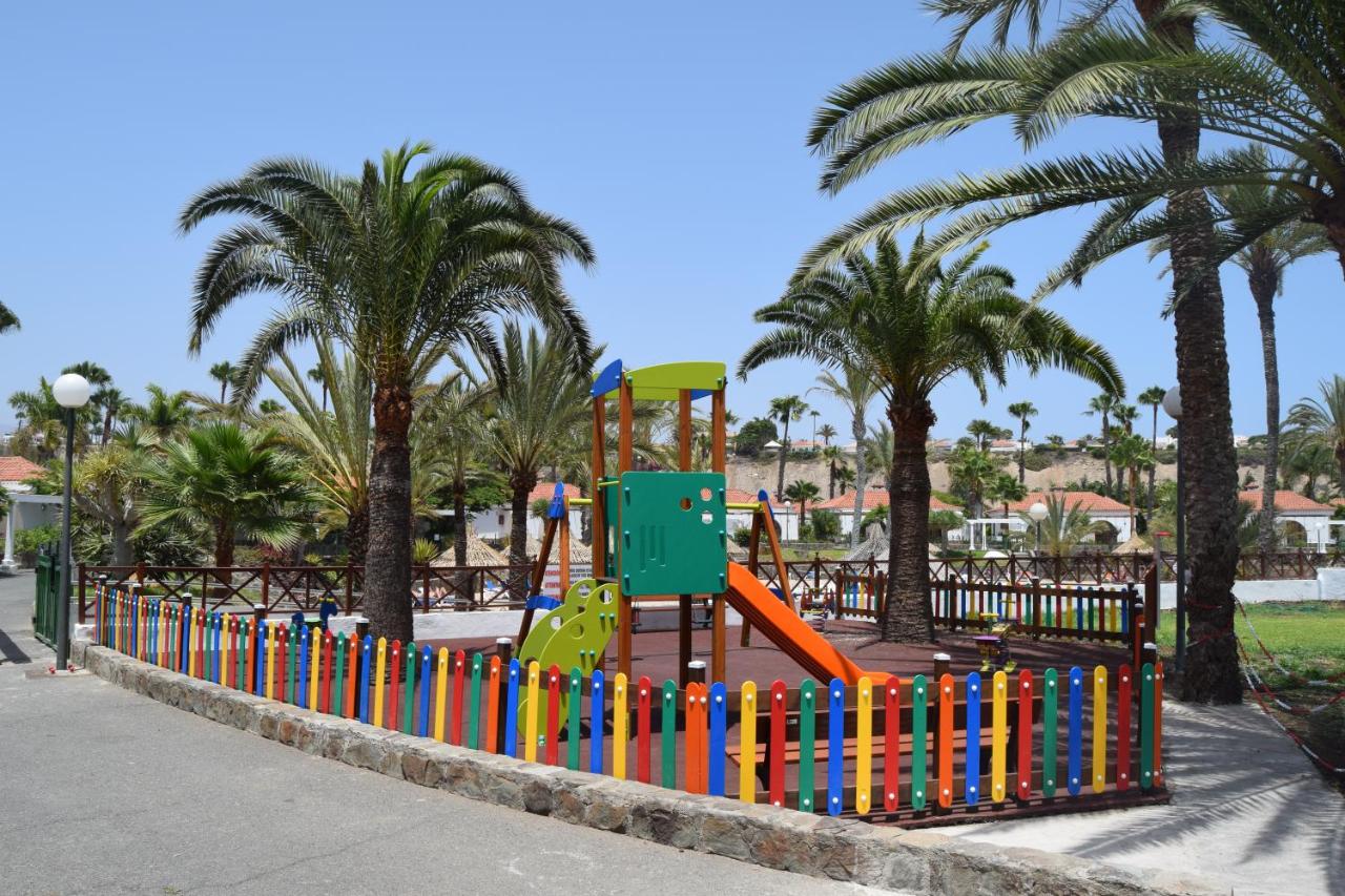 Children's playground with colourful fence and palm trees in the complex