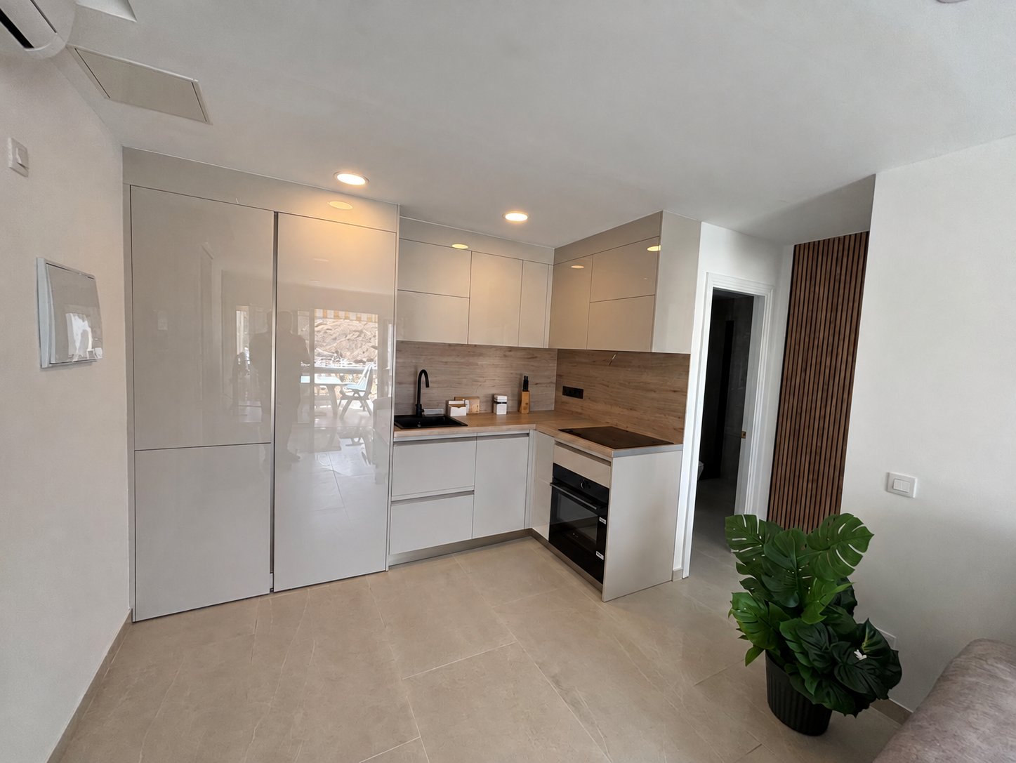 Modern open kitchen with oven, induction hob, fridge and wood-effect splashback